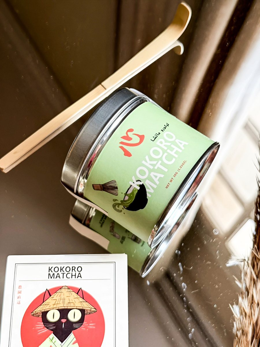 The Kokoro Matcha can lying on its side next to a bamboo scoop and a Kokoro card